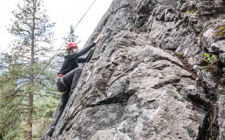 a student ascends a rock wall on a rock climbing expedition with outward bound